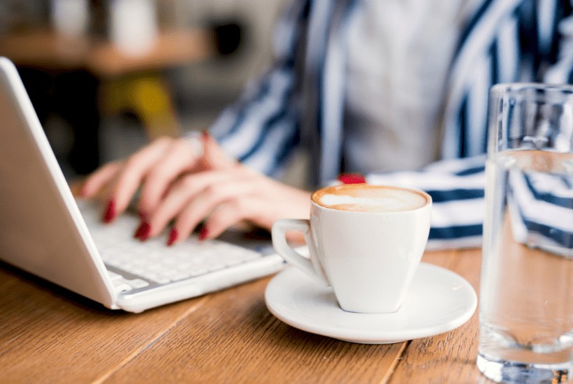 WOMAN TYPING ON LAPTOP DRINKING COFFEE READING PINTEREST TRENDS FOR JUNE